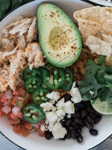 A chicken burrito bowl with veggies and chips.