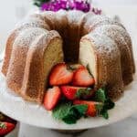 Sour cream pound cake with strawberries on a white cake stand.