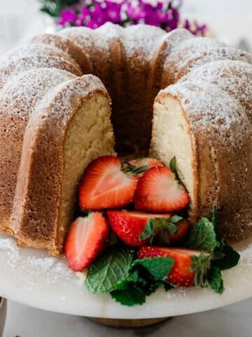 Sour cream pound cake with strawberries on a white cake stand.