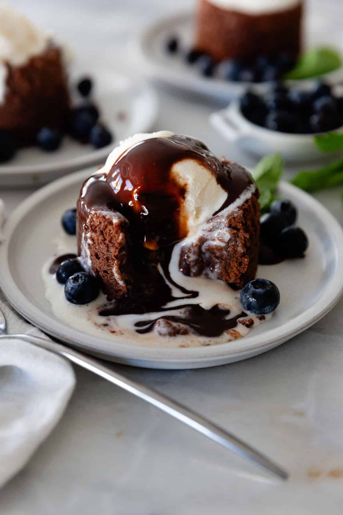 A chocolate lava cake on a plate with the chocolate oozing out and berries for garnish.