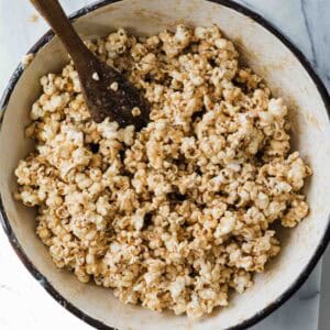 Salted caramel popcorn in a Dutch oven with a spoon in the pot.