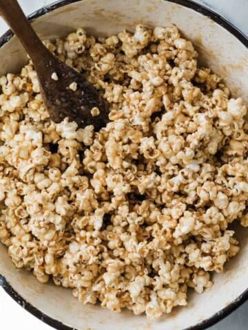 Salted caramel popcorn in a Dutch oven with a spoon in the pot.