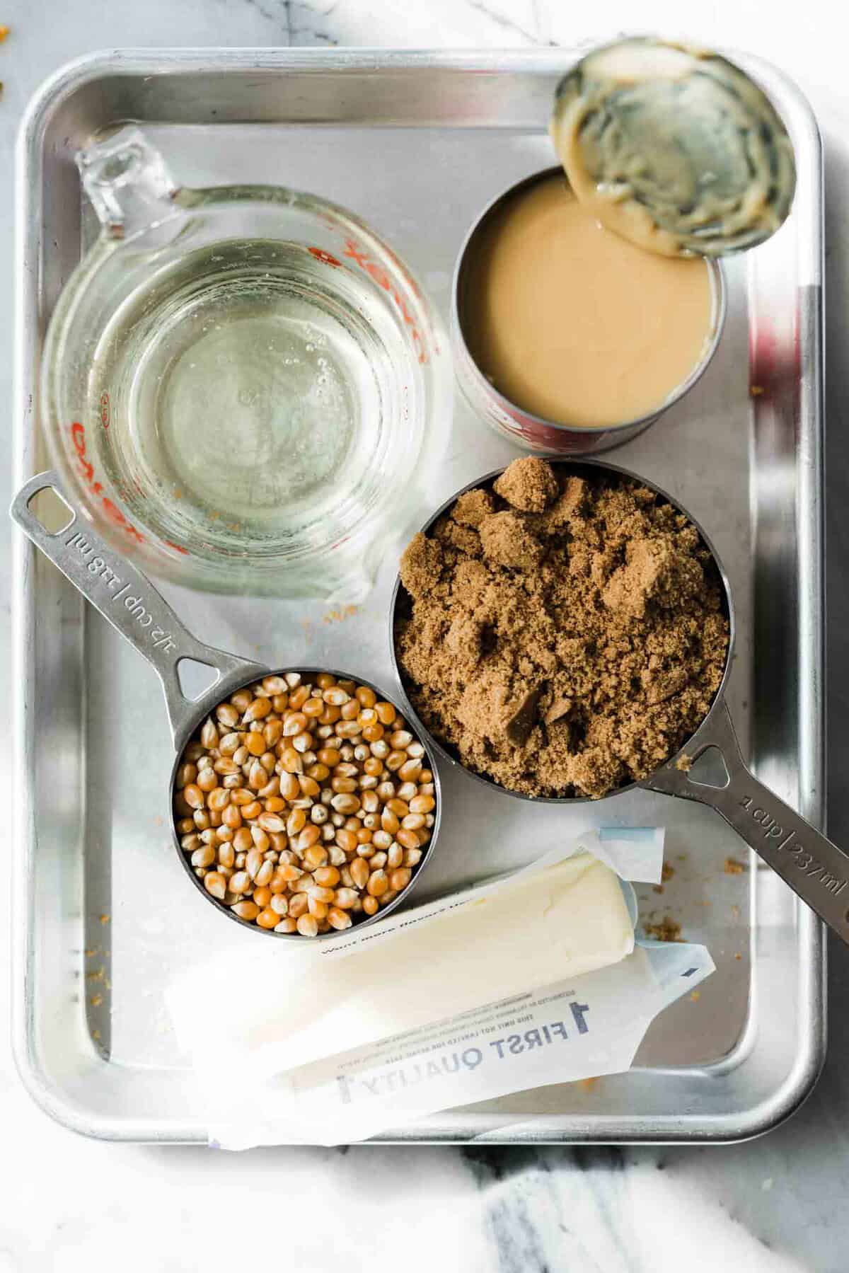Ingredients to make salted caramel popcorn on a metal pan. 