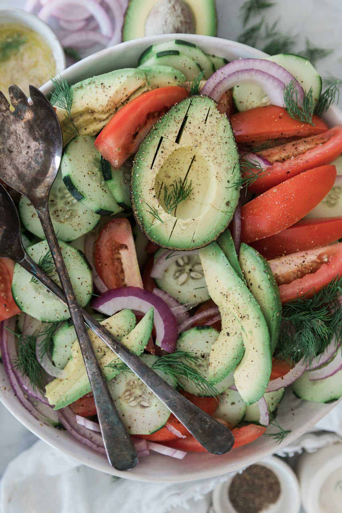 A salad with cucumber, tomato, onion and avocado.