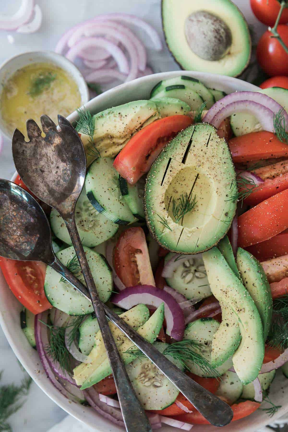 A salad with avocado, cucumber, tomato, onions.