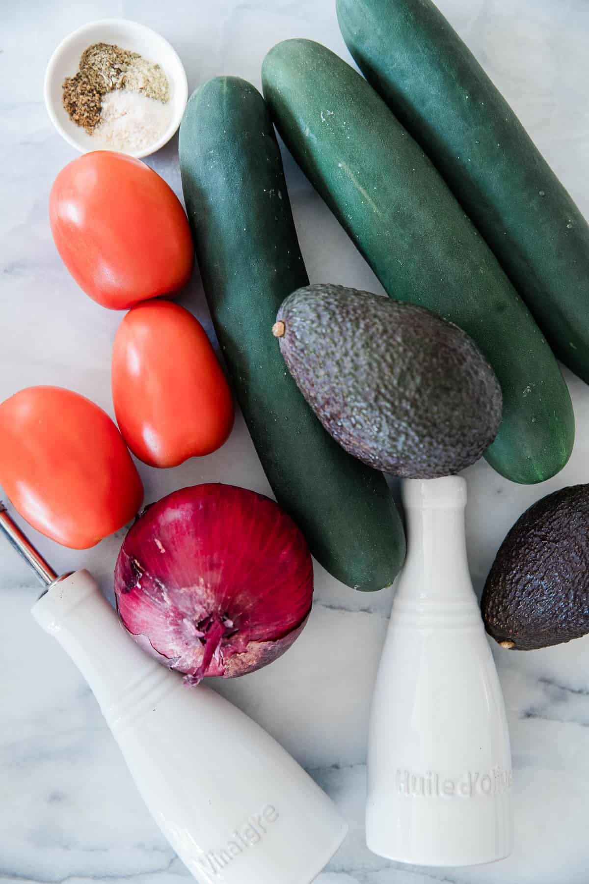 Ingredients to make this tomato and cucumber salad on a table.