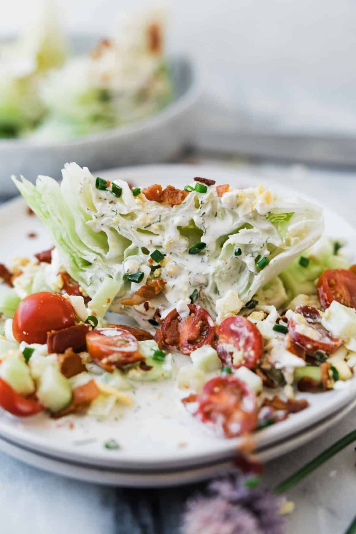 A wedge of iceberg lettuce, bacon, and tomatoes, covered in dressing.