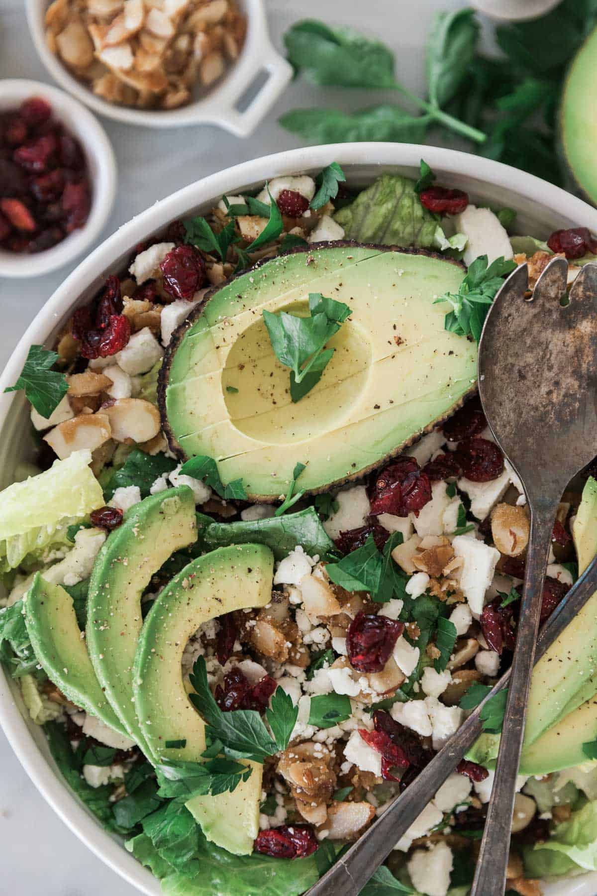 A bowl of salad with avocado on top.