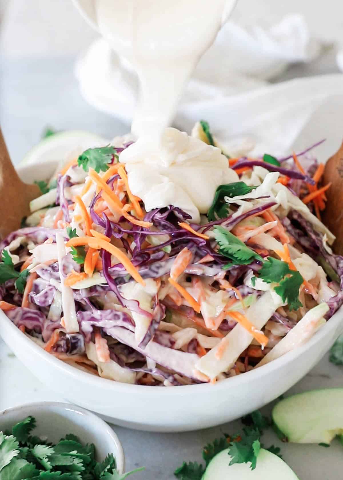 Dressing being poured over top of the coleslaw.