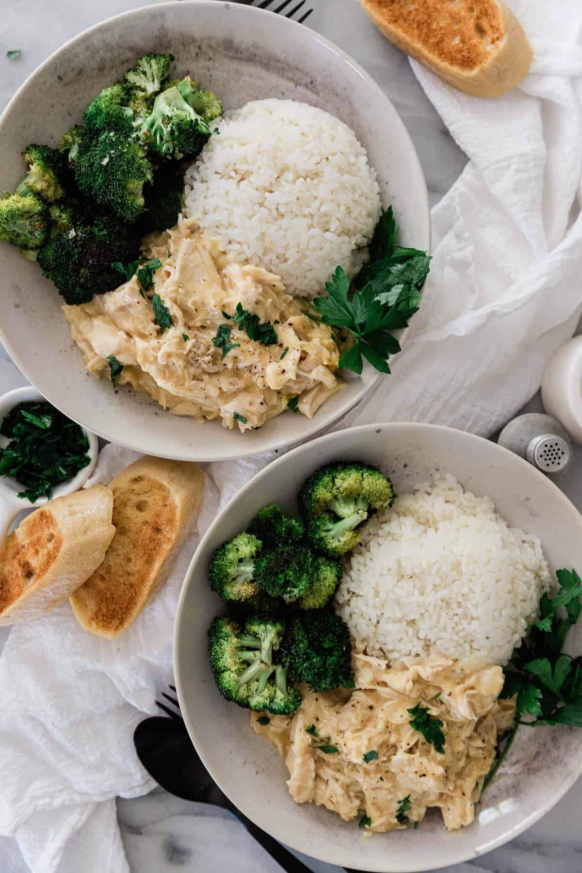 Two plates served with chicken, rice and broccoli.