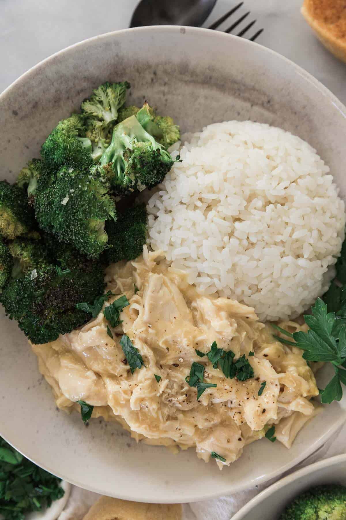 Smothered chicken served alongside rice and broccoli. 